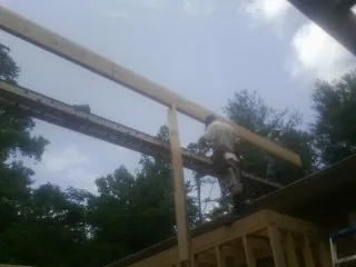 Carpenter setting a ridge beam over a new addition frame — Ice Dam Removal by Roofing Brothers in New Century