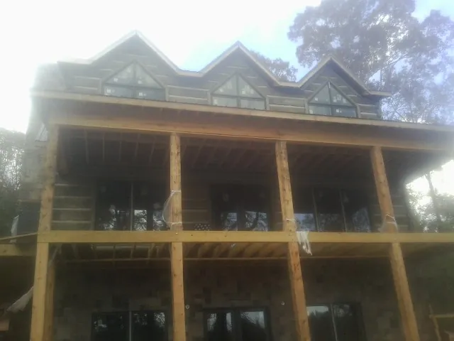 Dormers and porch framing on a large log home under construction — Roof Coating work by our crew in New Century