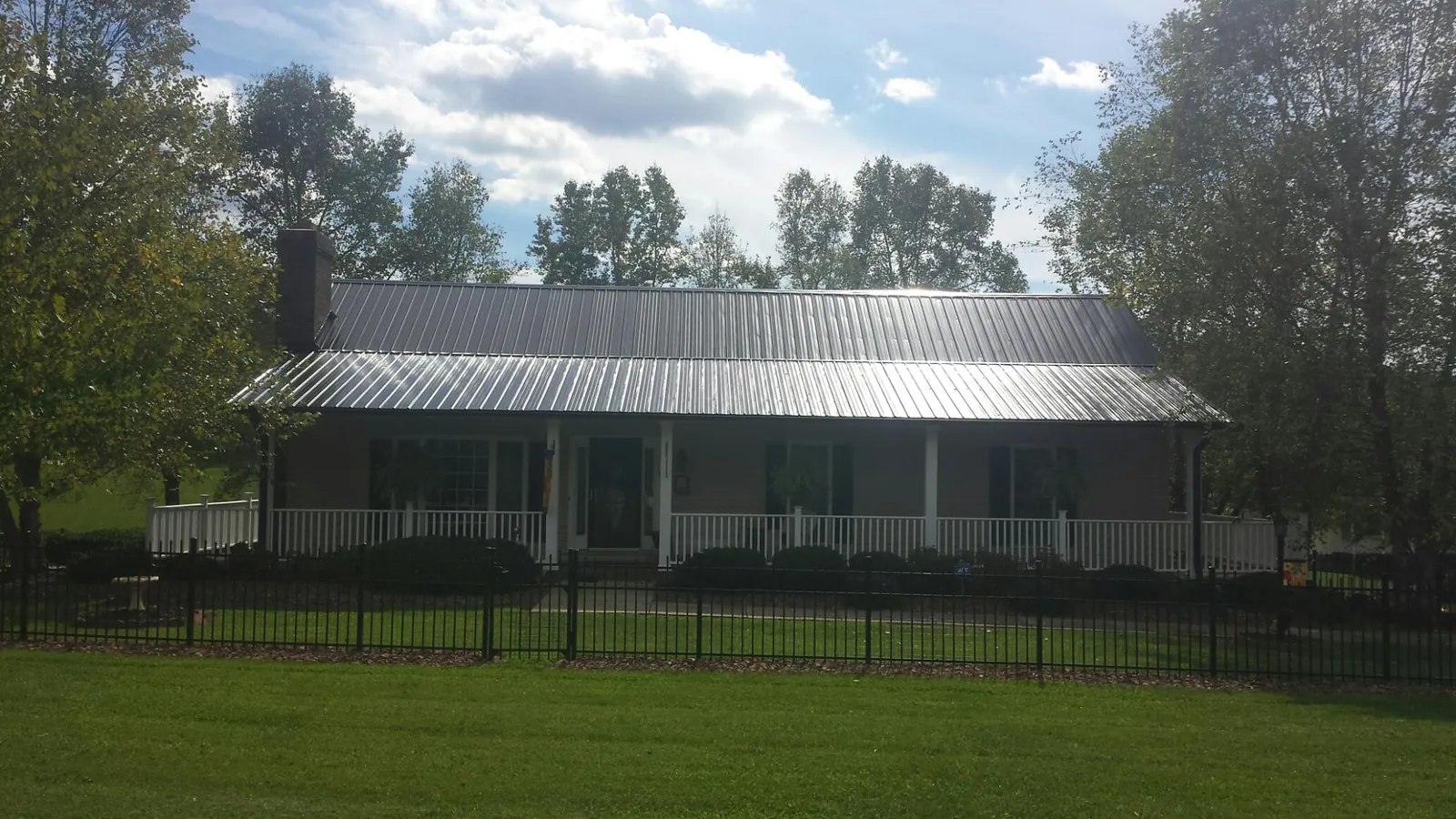 Gray metal roof on a brick ranch with a full width front porch — Gutter Guard Installation work by our crew in New Century