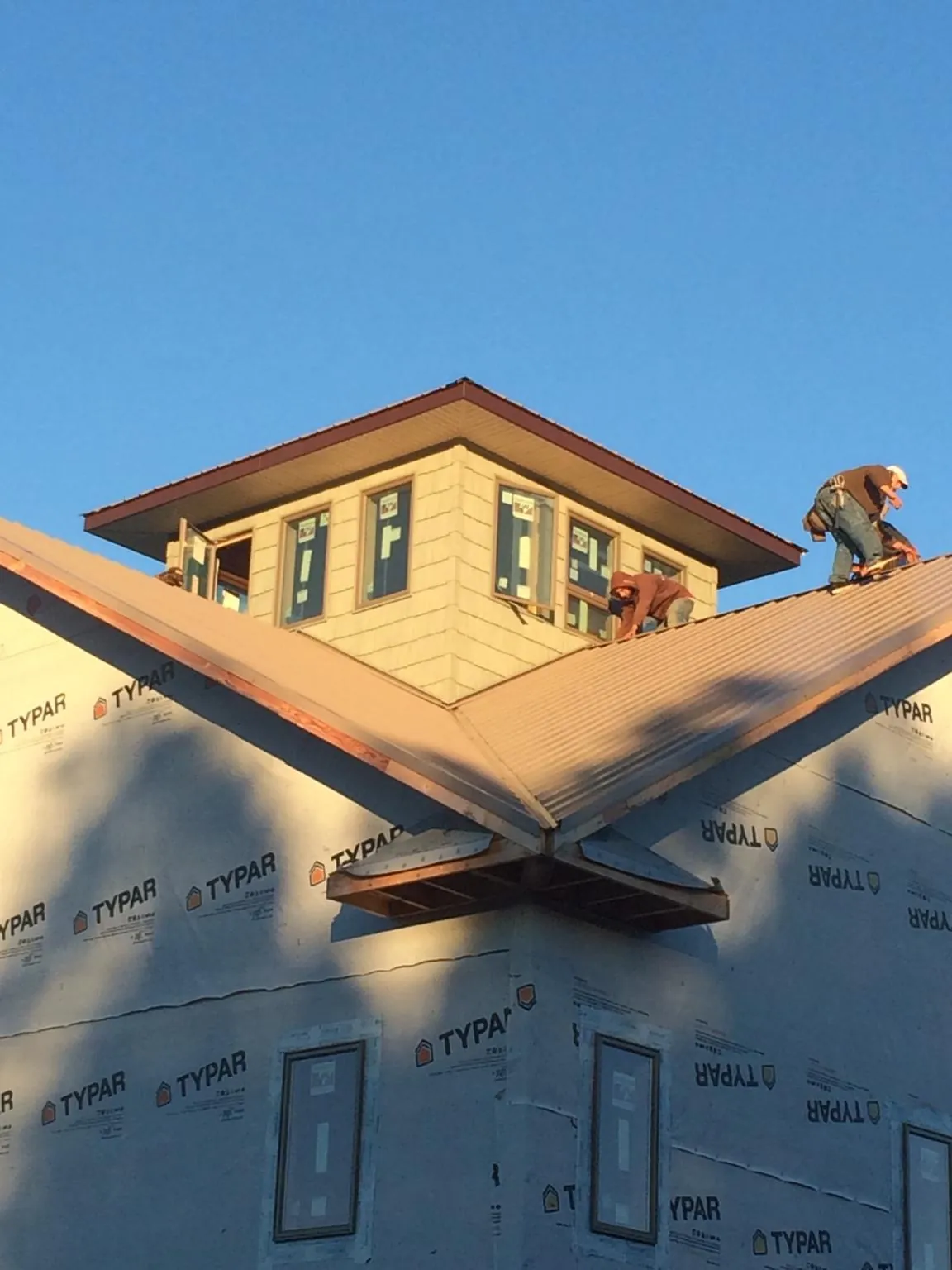 Roofers working around a rooftop cupola on a new metal roof at sunset — Roof Waterproofing in New Century by Roofing Brothers